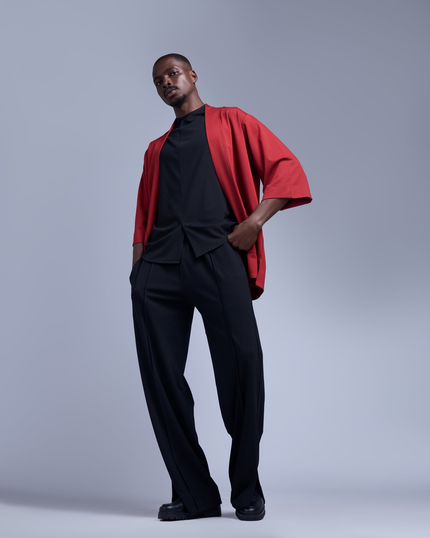 Man wearing a red jacket over a black outfit on a gray background