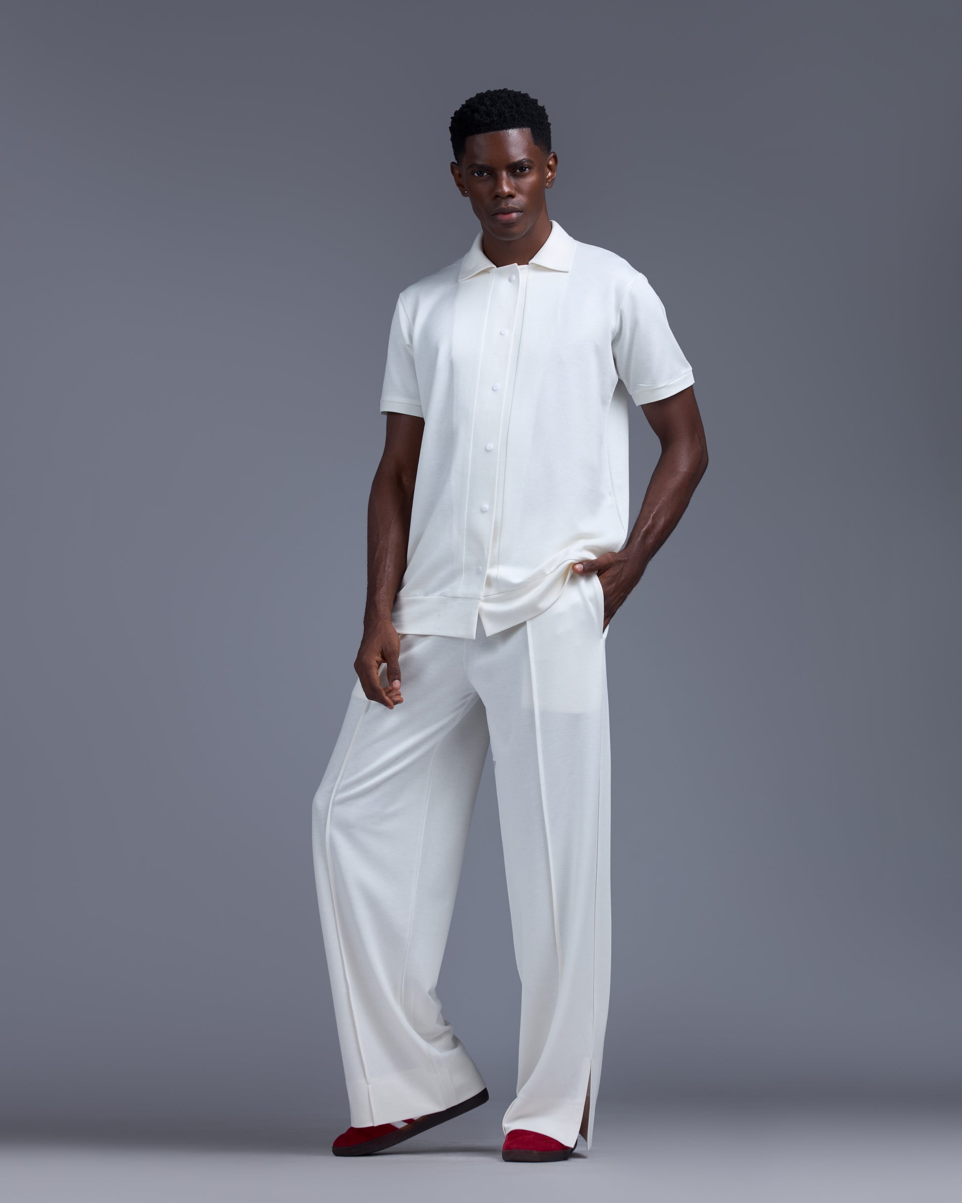 Man wearing a white outfit with red shoes on a gray background