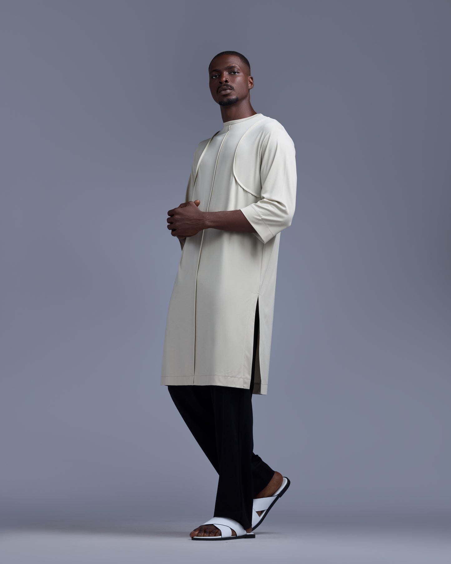 Man wearing a long beige garment against a gray background