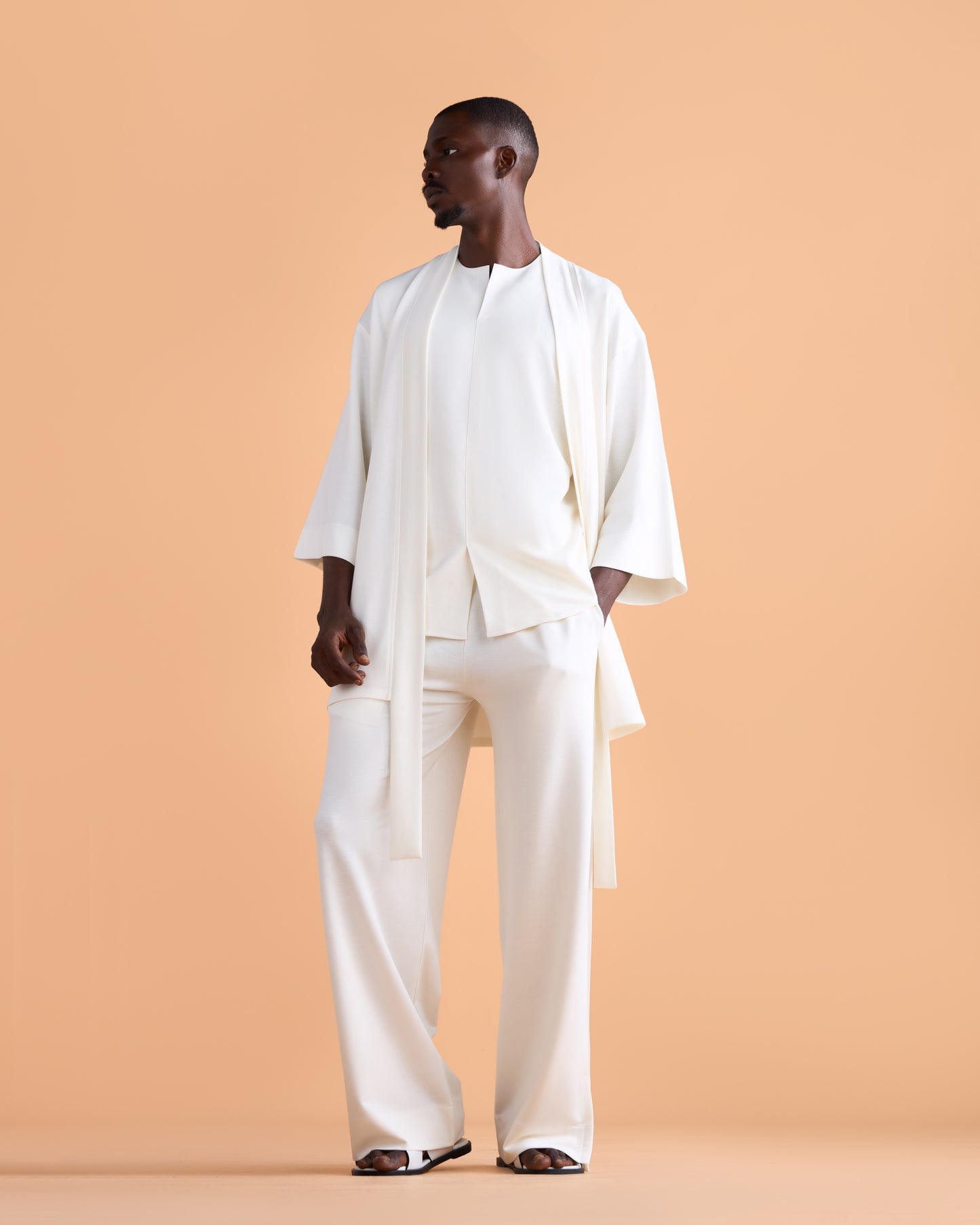 Man wearing a white outfit against a beige background