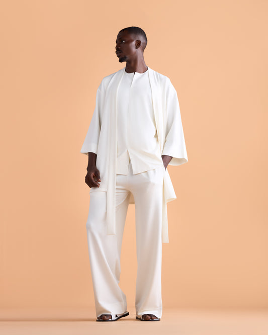 Man wearing a white outfit against a beige background